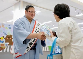 　地元住民（右）に交通安全グッズを手渡し握手する欧勝海関＝２６日午前、石川県津幡町