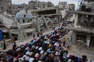 　イスラエルの攻撃で破壊されたモスクのそばで祈りをささげる人々＝２７日、パレスチナ自治区ガザ南部ハンユニス（ＡＰ＝共同）
