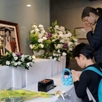 　朝日新聞阪神支局に設けられた拝礼所で、小尻知博記者の遺影に向かって手を合わせる人たち＝３日午前、兵庫県西宮市