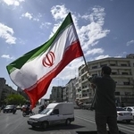 　イラン・テヘランの街頭で国旗を掲げる男性＝４月（共同）