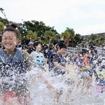 　水しぶきを上げて海に入る子どもたち＝４月、鹿児島県・奄美大島