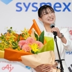 　現役引退の記者会見で花束を手にマイクを握るフィギュアスケート女子の坂本花織＝１３日午前、神戸市内のホテル