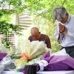 　空自機墜落事故から１年となり、献花台の前で手を合わせる人たち＝１４日午後、愛知県犬山市