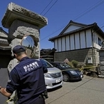 　強盗殺人事件現場の住宅に規制線を張る警察官＝１７日午前、栃木県上三川町