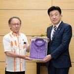　沖縄県の玉城デニー知事（左）から「かりゆしウエア」を贈呈される木原官房長官＝２２日午前、首相官邸