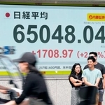 　上げ幅が一時１７００円を超え、取引時間中の最高値を更新し初めて６万５０００円台に乗せた日経平均株価を示すモニター＝２５日午前、東京都中央区