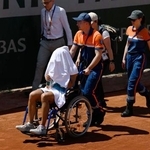 　女子シングルス１回戦の第３セットで途中棄権し、車いすで運ばれる内島萌夏（手前）＝パリ（共同）