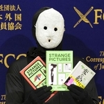 　記者会見で著書を手にする覆面作家の雨穴さん＝２０２５年１月、東京都千代田区の日本外国特派員協会