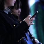 　東京・渋谷のスクランブル交差点で、スマートフォンを手にする人＝２０２５年２月
