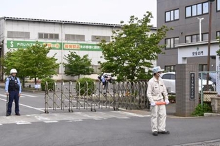 　クマに従業員が襲われた「福島製鋼」事業所の入り口付近で警戒する警察官や関係者＝２日午前８時５４分、福島市