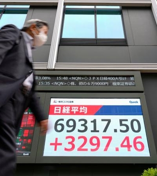 　初めて６万９０００円を突破して最高値を更新した日経平均株価終値を示すモニター＝１５日午後、東京都中央区
