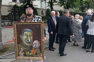 　１２日、ドイツ・ベルリンのロシア大使館前でプーチン氏の風刺画を掲げるセミョーン・スクレペツキー氏（同氏のテレグラムから・共同）