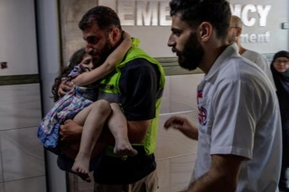 　２０日、レバノン南部の病院で、イスラエルによる攻撃で負傷した少女を搬送する人（ロイター＝共同）