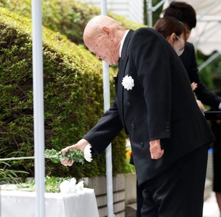 　式典で献花する違憲国賠訴訟全国原告団協議会の竪山勲会長＝２２日午前、厚労省