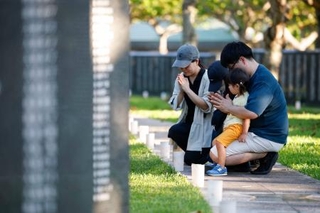 　「慰霊の日」を前に、沖縄戦犠牲者の名前が刻まれた「平和の礎」に手を合わせる家族連れ＝２２日午後、沖縄県糸満市の平和祈念公園