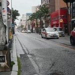 　雨と強い風の中、国際通りを走行する車＝１日午前、那覇市