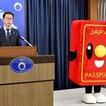 　記者会見する北村俊博外務報道官とパスポートのイメージキャラクター「パスポくん」＝５月、外務省