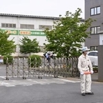 　クマに従業員が襲われた「福島製鋼」事業所の入り口付近で警戒する警察官や関係者＝２日午前８時５４分、福島市