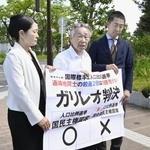 　衆院選の「１票の格差」訴訟の判決を受け、仙台高裁秋田支部前で「ガリレオ判決」などと書かれた紙を掲げる原告側の升永英俊弁護士（中央）ら＝５日午後