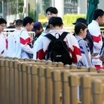 　中国の全国一斉大学入試「高考」の会場前で所持品をチェックされる学生＝７日、北京（共同）
