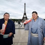 　大相撲パリ公演を前に、エッフェル塔の前でフランスパンを食べる大の里（右）と豊昇龍の両横綱＝１１日、パリ（共同）