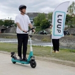 　鴨川沿いの河川敷を電動キックボードで走行する「Ｌｕｕｐ」の社員＝２３日午前、京都市