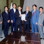 　選挙運動に関するＳＮＳ対策に向けた法改正案を衆院の築山信彦事務総長（中央右）に提出する与野党の議員ら＝２４日午後、国会