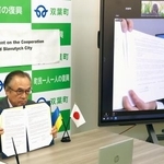 　原発事故に関する知見の共有に向けた連携協定の締結式をオンラインで開き、署名した福島県双葉町の伊沢史朗町長（左）とスラブチチ市のフォミチェフ市長＝２６日午後、双葉町役場