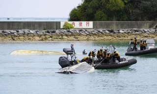 　海上保安庁の職員らにえい航される転覆した船２隻＝３月、沖縄県名護市の辺野古漁港