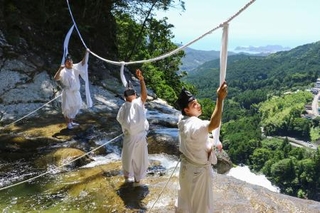 　「那智の滝」の上に架かる大しめ縄を張り替える神職＝９日午前、和歌山県那智勝浦町