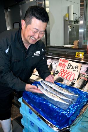 　１匹８万８８８０円の値が付いたサンマを見つめ、笑顔を見せる水産加工会社マルサ笹谷商店の笹谷剛社長＝９日午前、北海道釧路町