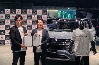 　協業を発表した三菱自動車の加藤隆雄会長兼ＣＥＯ（右）とハイランダーズの増岡宏哉ＣＥＯ。車の手前は人型ロボット＝９日午後、東京都港区