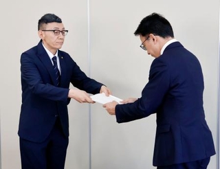 　宮城県名取市役所で、第三者委員会の鎌田健司委員長（右）から中学３年の男性の飛び降りに関する報告書を受けとる教育長＝１０日午前