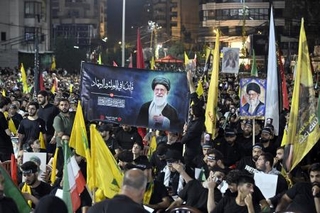 　レバノンの首都ベイルートで、イランの前最高指導者アリ・ハメネイ師を追悼するため写真やイラン国旗を掲げる人々＝８日（ゲッティ＝共同）
