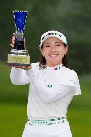 　通算１９アンダーで優勝し、トロフィーを手に笑顔の永井花奈＝真駒内ＣＣ