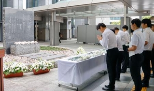 　小学女児らが死亡した集団食中毒から３０年となり、堺市役所前の追悼式典で献花し、祈りをささげる参列者＝１２日午後