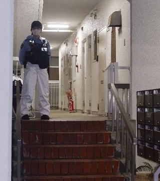 　冷凍庫に入った男性の遺体が見つかった集合住宅を警戒する警察官＝６月２０日、神戸市中央区