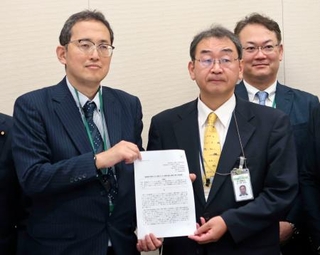 　厚労省幹部（手前右）に緊急提言を提出する全がん連の天野慎介理事長＝１４日午前、国会