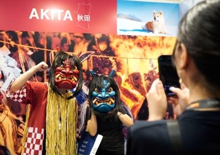 　「トラストバンク」のブースでナマハゲに扮（ふん）して写真に納まる来場者＝１５日、香港（共同）