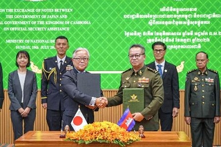 　カンボジアの首都プノンペンで開かれた署名式に出席する植野篤志駐カンボジア大使（手前左）とティア・セイハ副首相兼国防相（手前右）＝１９日（外務省提供）