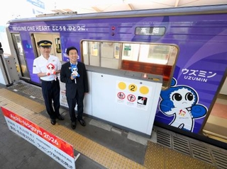 　アジア・アジアパラ競技大会に向け、公式マスコットが描かれた名古屋市営地下鉄の車両と写真に納まる広沢一郎市長（右）ら＝２３日午前、名古屋市
