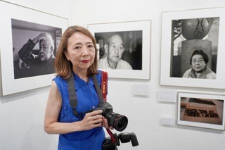 　樺太引き揚げ者を写した写真展で、自身の作品の前に立つ広瀬明代さん＝２７日午後、東京都新宿区