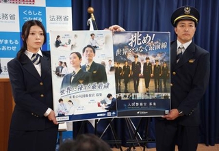 　採用案内のポスターを掲げる出入国在留管理庁の職員＝２８日午前、法務省