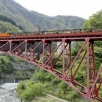 　鉄橋を渡る黒部峡谷鉄道のトロッコ電車＝４月、富山県黒部市