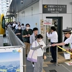 　累計利用者数が１５００万人を超えたＬＲＴ「ライトライン」の宇都宮駅東口停留所で行われた記念品の配布＝９日午後