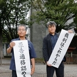 　上告審判決を受け、最高裁前で「原告適格認める」と書かれた紙を掲げる原告の金城武政さん（左）＝１３日午後