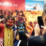 　「トラストバンク」のブースでナマハゲに扮（ふん）して写真に納まる来場者＝１５日、香港（共同）