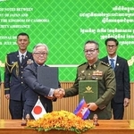 　カンボジアの首都プノンペンで開かれた署名式に出席する植野篤志駐カンボジア大使（手前左）とティア・セイハ副首相兼国防相（手前右）＝１９日（外務省提供）