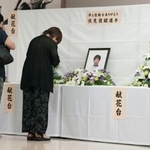 　高知競輪場に設置された伏見俊昭さんの献花台で手を合わせる人たち＝２０日、高知市