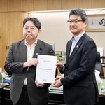 　地方税収の偏在是正を求める提言書を林総務相（左）に手渡す宮崎県の河野俊嗣知事＝２２日午後、総務省